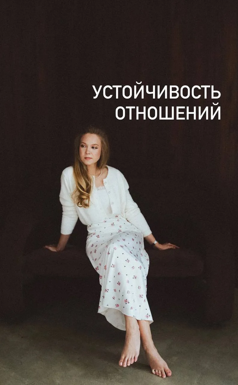 Полина Дворецкая сидит на фоне красных зановесок в белоснежном платье и босыми ногами